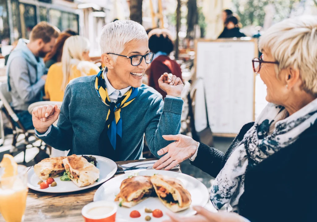 Two women laughing together over lunch at a restaurant